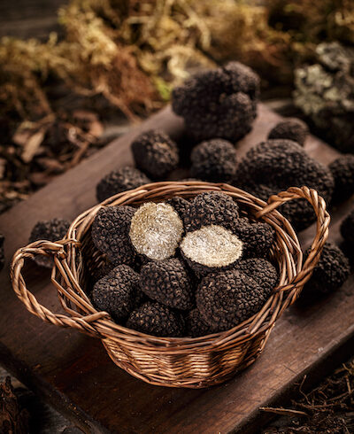 a basket of black truffles on a wooden board